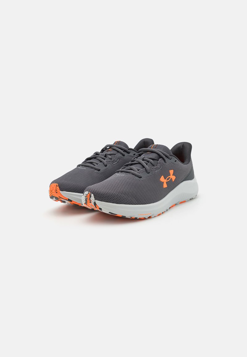 Des chaussures de sport légères avec une tige en mesh gris, des accents orange et une semelle grise flexible dotée de motifs de traction texturés.