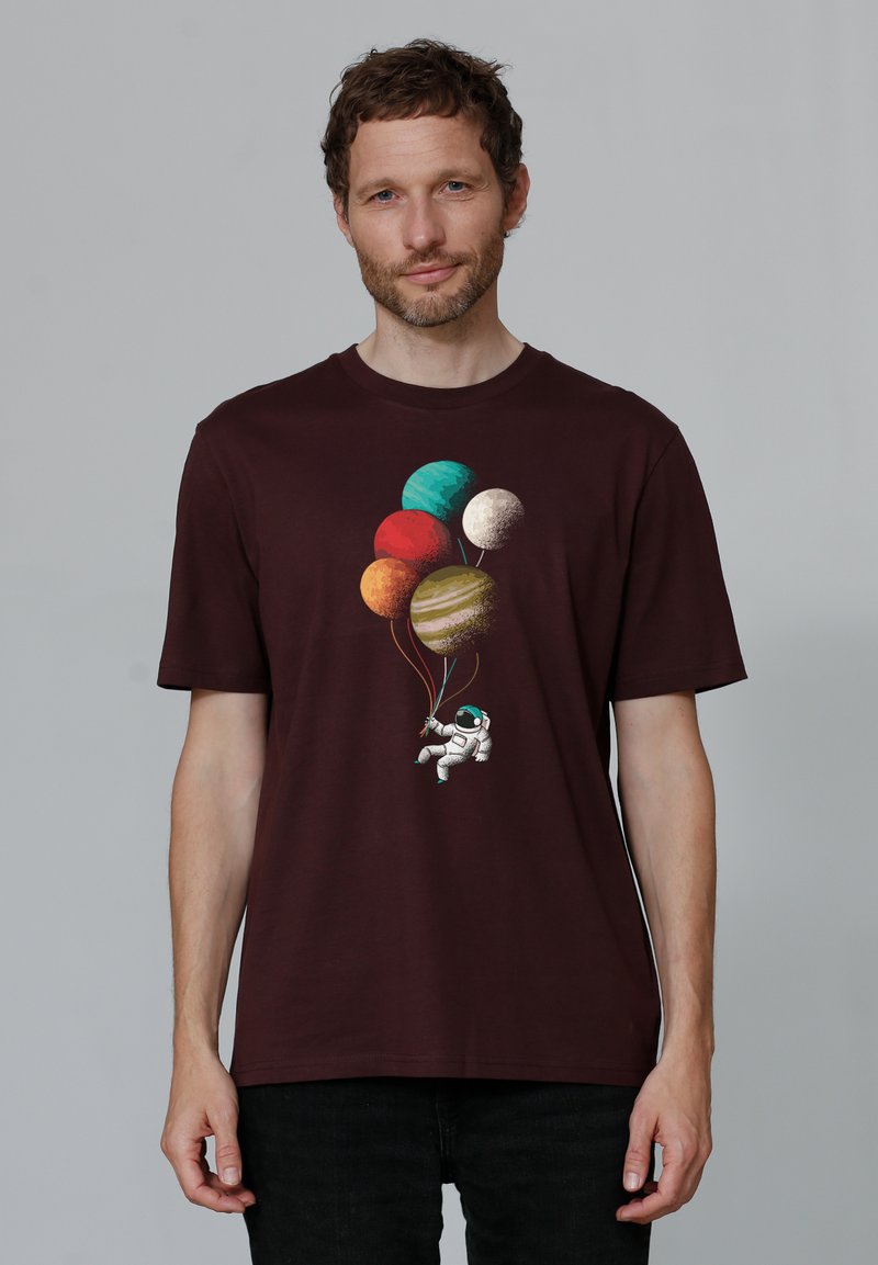 T-shirt en coton bordeaux avec un graphisme d'astronaute tenant des ballons-planètes colorés, col ras du cou et coupe décontractée.