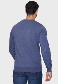 Heathered blauwe sweatshirt met lange mouwen, ribbelboorden en -zoom, eenvoudig ontwerp, zachte textuur en een klein detail met een naad aan de achterkant.