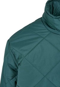 Quilted grøn pufferjakke med høj krave, der har en glat tekstur og diamantmønstret syning. Materialet virker let og isoleret.