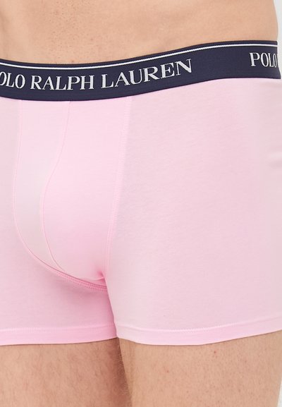 Roza bokserice z oprijetim dizajnom, izdelane iz mehkega materiala. Imajo morsko modro elastično pasnico z belim logotipom "POLO RALPH LAUREN".
