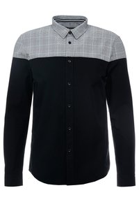 Skjorta med lång ärm som har en svart kropp och en grå rutig yoke. Tillverkad av bomull med knäppningar och klassisk krage.