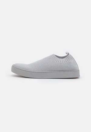 Zapatilla deportiva gris claro sin cordones con parte superior de tejido de punto, cuello acanalado en el tobillo y suela de goma plana, mostrada de perfil sobre un fondo blanco.