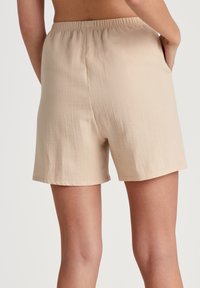 Beige, lichte shorts met een elastische tailleband, zakken en een gestructureerd oppervlak, met een losse pasvorm voor comfort.