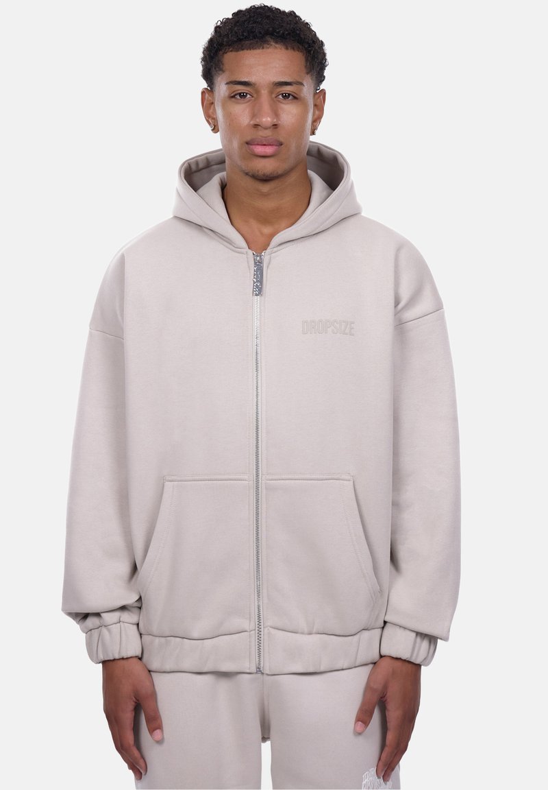 Lys grå zip-up hoodie med en stor hætte, forlommer, ribbede manchetter og et præget brandlogo. Fremstillet af blødt, tekstureret stof.