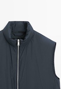 Granatowa puchowa kamizelka z wysokim kołnierzem i przednim zamkiem błyskawicznym. Charakteryzuje się bezrękawnikowym krojem i gładką fakturą, idealna do noszenia warstwowego lub na przejściową pogodę.