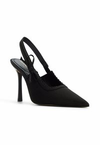 Zapato de tacón alto negro tipo slingback en tela con punta afilada, bordes con ondas y un tacón delgado. Presenta una correa ajustable para un mejor ajuste.