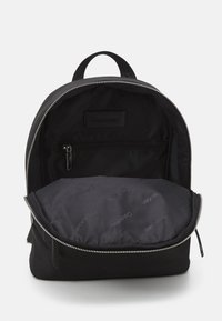 Black backpack made of fabric with a smooth texture, featuring a silver zipper and a logo patch. The interior has a similar color scheme and design.