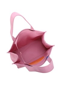 Borsa tote in tela rosa con ampie spalline in tessuto, apertura superiore e tasca interna con un accento arancione. Texture liscia, forma non strutturata.