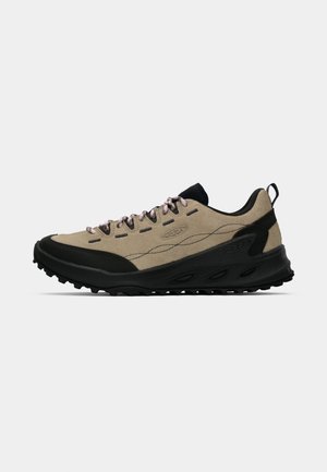 Beige and black low-top hiking shoe with rugged sole, pink laces, and pull tab on heel, designed for outdoor use.