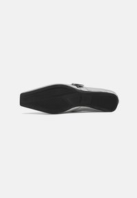 Black leather shoe with a pointed toe design, featuring a smooth upper and a textured rubber sole with patterned grooves for grip.