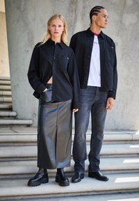 Črna srajca na ženski, v kombinaciji z visokim črnim usnjene krilo. Moški v črni srajci čez belo majico z sivo jeans hlačami. Črne čevlje.
