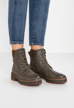 Bottines en cuir brun avec un design à lacets, une fermeture éclair sur le côté, une surface texturée et une semelle robuste avec des crampons profonds.