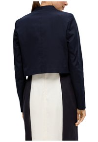 Navy cropped jasje met lange mouwen, een gladde textuur, zonder knopen, ronde halslijn, gecombineerd met een wit en navy kleur blok jurk.
