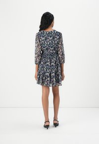 Rochie cu imprimeu floral, cu talie ajustată, mâneci lungi transparente și o margine fustă cu volane în straturi. Materialul are o combinație de culori violet, roz și verde.