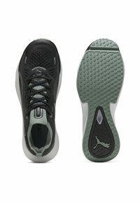 Chaussures de sport noires avec une tige en mesh respirant, rehaussées de détails vert clair ; dotées d'une semelle en caoutchouc texturée avec un logo.
