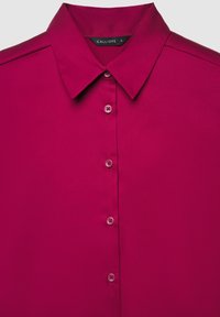 Bright magenta button-up shirt with pointed collar and a visible black size label "CALLIOPE S" at the neckline.