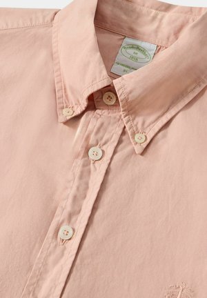 Camicia button-up rosa chiaro in cotone, con colletto a punta, dettagli cuciti e quattro chiusure a bottone. Logo ricamato sul davanti.