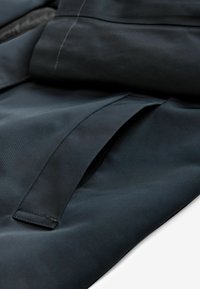 Țesătură neagră cu o textură netedă, mată. Are piese suprapuse și un detaliu de cusătură. Designul sugerează o construcție a îmbrăcămintei bine structurată.