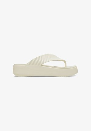 Light beige flip-flop sandal with a textured, curved thong strap and a thick, flat sole. Features a ridged design on the strap.