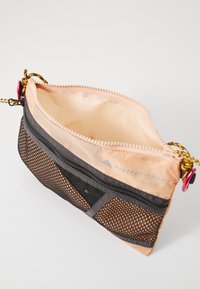 Torba s patentnim zatvaračem s breskvastim najlonskim gornjim dijelom, crnim mrežastim dnom i šarenom špagu. Sadrži logotip i složeni detalj šivenja.