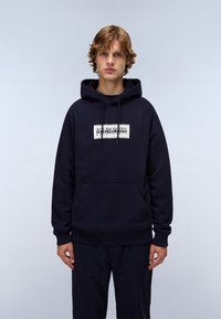 Felpa blu navy con tasca a marsupio frontale, cordini al colletto e logo stampato bianco. Ha una texture morbida e una vestibilità comoda.