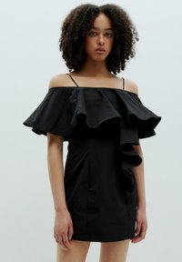 Schwarzes schulterfreies Kleid mit Rüschensäumen, tailliertem Oberteil und glatter Textur. Verfügt über dünne Träger und einen knielangen Schnitt.