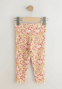 Virágmintás leggings bordázott anyagból, piros, narancs és zöld mintákkal világos alapon. Hullámos szegéllyel és elasztikus derékpánttal rendelkezik.