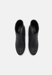 Bottines noires en matière texturée avec un léger scintillement, dotées d'un col lisse et d'une fermeture éclair latérale pour un enfilage facile.