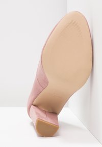 Růžová semišová dámská bota na podpatku, se čtveratou špičkou a masivním podpatkem. Podešev je béžová s vodorovnými drážkami pro lepší přilnavost. Čistý design, bez viditelných ozdob.