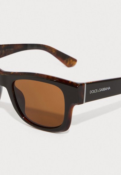 Tortoiseshell saulesbrilles ar brūniem tonētiem stikliem, kvadrātveida forma, spīdīga plastmasas apmale un sudraba akcents ar "Dolce & Gabbana" logotipu.