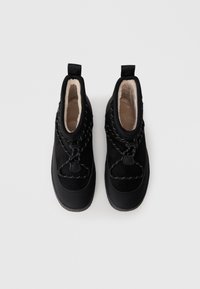 Zwarte schoenen met een suède bovenkant, zachte voering, elastische veters en een rubberen zool. Bevat een verhoogde achterkant voor ondersteuning en een zachte afwerking.