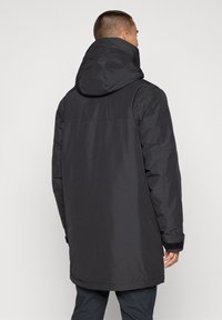 Svart huva jacka med en slät, matt yta. Har en avslappnad passform, justerbara ärmslut och en medellång design för bra täckning.