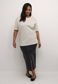 Gestreepte t-shirt met korte mouwen in crème met grijze strepen, gecombineerd met een donker denim midi-rok met een voorkeursplit, gedragen met zwarte flats.