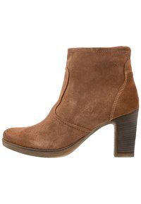 Bruine suède enkellaars met een ronde neus, zijnaaddetail en een gestapelde hak. De zool is van rubber voor extra grip.