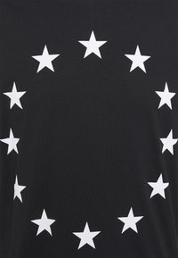 Černé tričko s kruhovým uspořádáním bílých hvězd, které má hladkou texturu a jednoduchý design.
