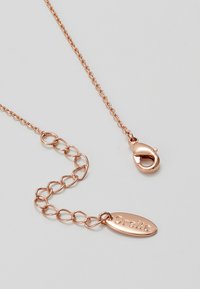 Halskette aus Roségold mit miteinander verbundenen Kettengliedern, ausgestattet mit einem Verschluss und einem Anhänger, der mit "Orelia" graviert ist, und hebt eine glatte metallische Oberfläche hervor.