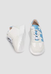Baskets blanches et bleu clair avec des matériaux en daim et en cuir, bout rond, design à lacets, semelle texturée et accents bleus sur les côtés.
