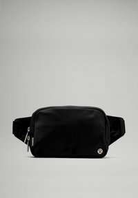 Bolsa de hombro de nailon negra con forma rectangular, cierre con cremallera y un pequeño logotipo en el frente. Textura suave y correa ajustable.