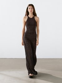 Jumpsuit nero in maglia con top aderente e gambe svasate. Caratterizzato da un design con collo all'americana e tessuto testurizzato, abbinato a scarpe con plateau.