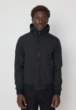 Veste zippée noire avec capuche, poignets et ourlet élastiques. Tissu extérieur lisse, design minimaliste, dotée d'une fermeture éclair à l'avant.