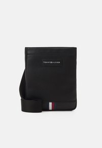Borsa a tracolla in pelle nera con superficie testurizzata, dotata di un patch logo frontale e accenti colorati in rosso, bianco e blu nella parte inferiore.