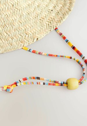 Chapeau en paille tressée avec des sangles en perles colorées, présentant diverses teintes, une forme ronde et un accent central en perle en bois.