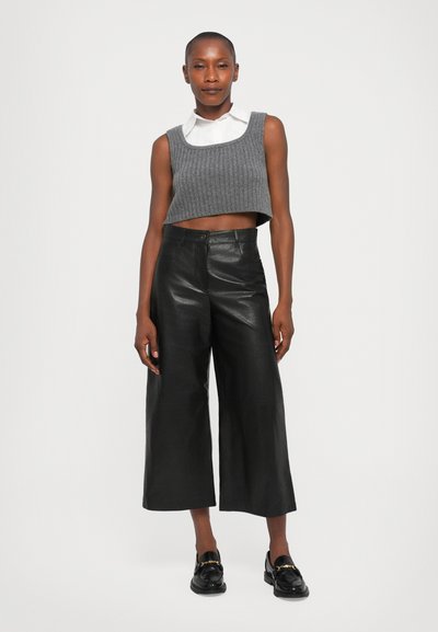 Gråstripet crop topp med firkantet hals, kombinert med høyt midje svarte skinn culottes. Svarte loafers fremhever antrekket.