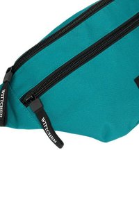 Tyrkysová látková ledvinka s dvěma černými zipy, texturovaný materiál a značka WITTCHEN na popruzích. Kompaktní a funkční design.