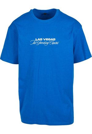 Sinine puuvillane T-särk lühikeste varrukatega. Ees on valge tekst, mis ütleb "LAS VEGAS Hasartmängude Pealinn" erinevates fontides.
