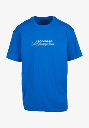 Blå bomulds T-shirt med korte ærmer. Foran er der hvid tekst med teksten "LAS VEGAS The Gambling Capital" i forskellige skrifttyper.