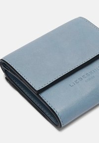 Jasnoniebieski skórzany portfel o gładkiej fakturze, prostokątnym kształcie i wytłoczonym logo. Posiada przeszycia wzdłuż krawędzi i projekt składany.