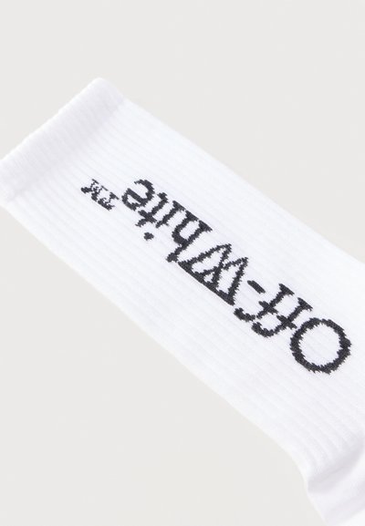 Λευκό ριμπ ύφασμα με μαύρο κεντημένο κείμενο «Off-White» σε γοτθική γραμματοσειρά κατά μήκος.