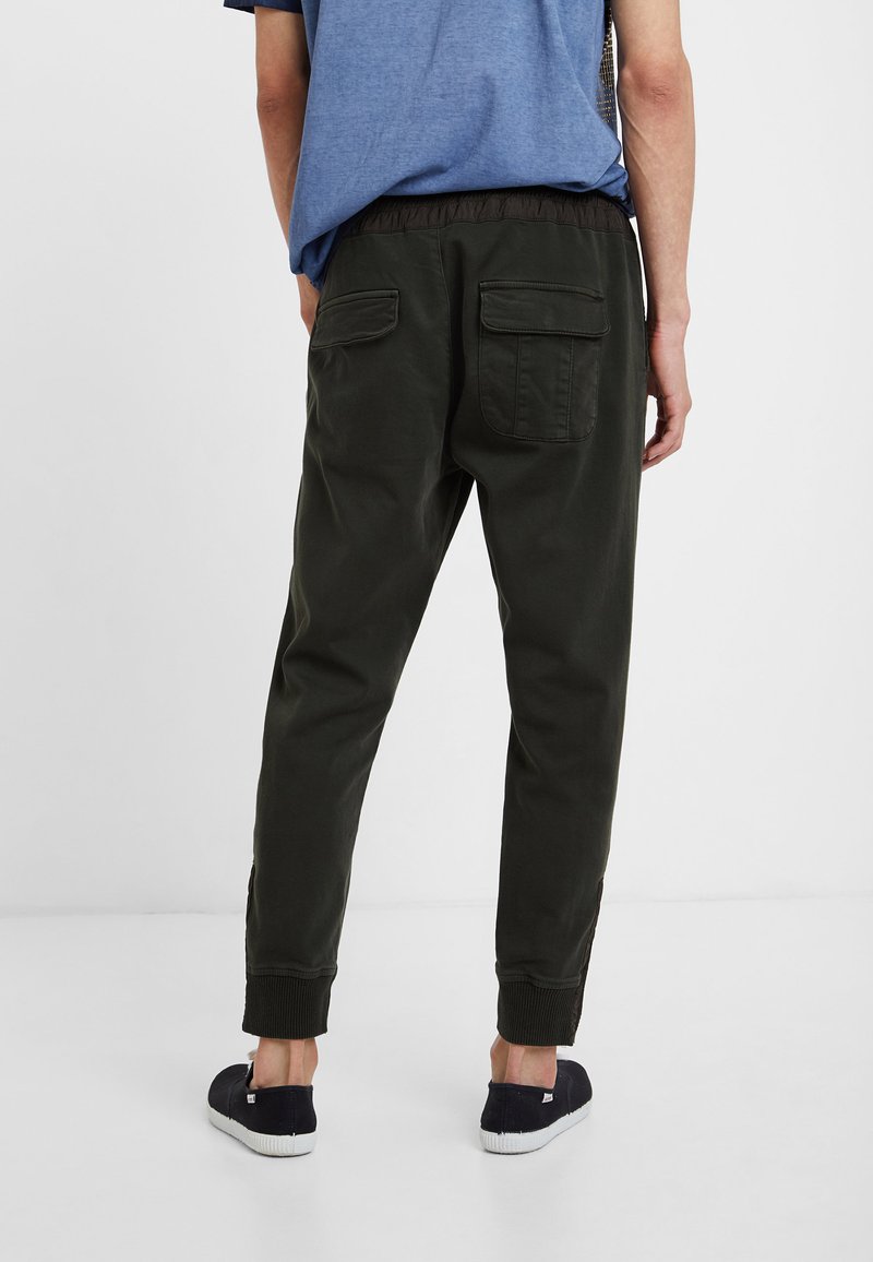 Dunkelgrüne Jogginghosen mit einem elastischen Bund, umgeschlagenen Säumen und zwei Gesäßtaschen. Hergestellt aus einem weichen, atmungsaktiven Stoff.